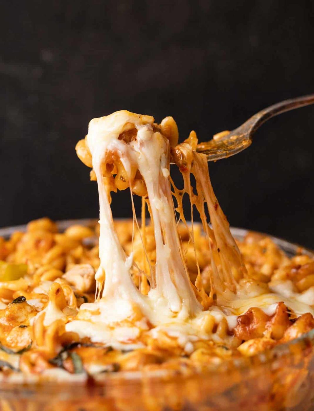 Closeup of air fryer baked pasta in red sauce being eaten with a fork