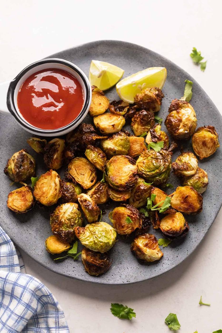 Roasted air fryer brussel sprouts served on a grey plate with ketchup on the side