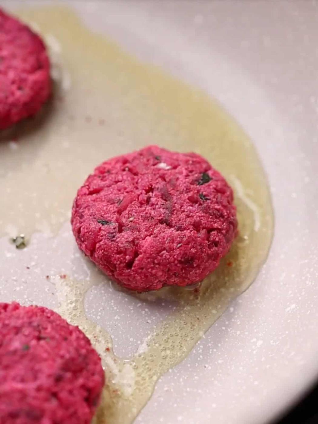 close up shot of beetroot tikkis shallow frying in a pan