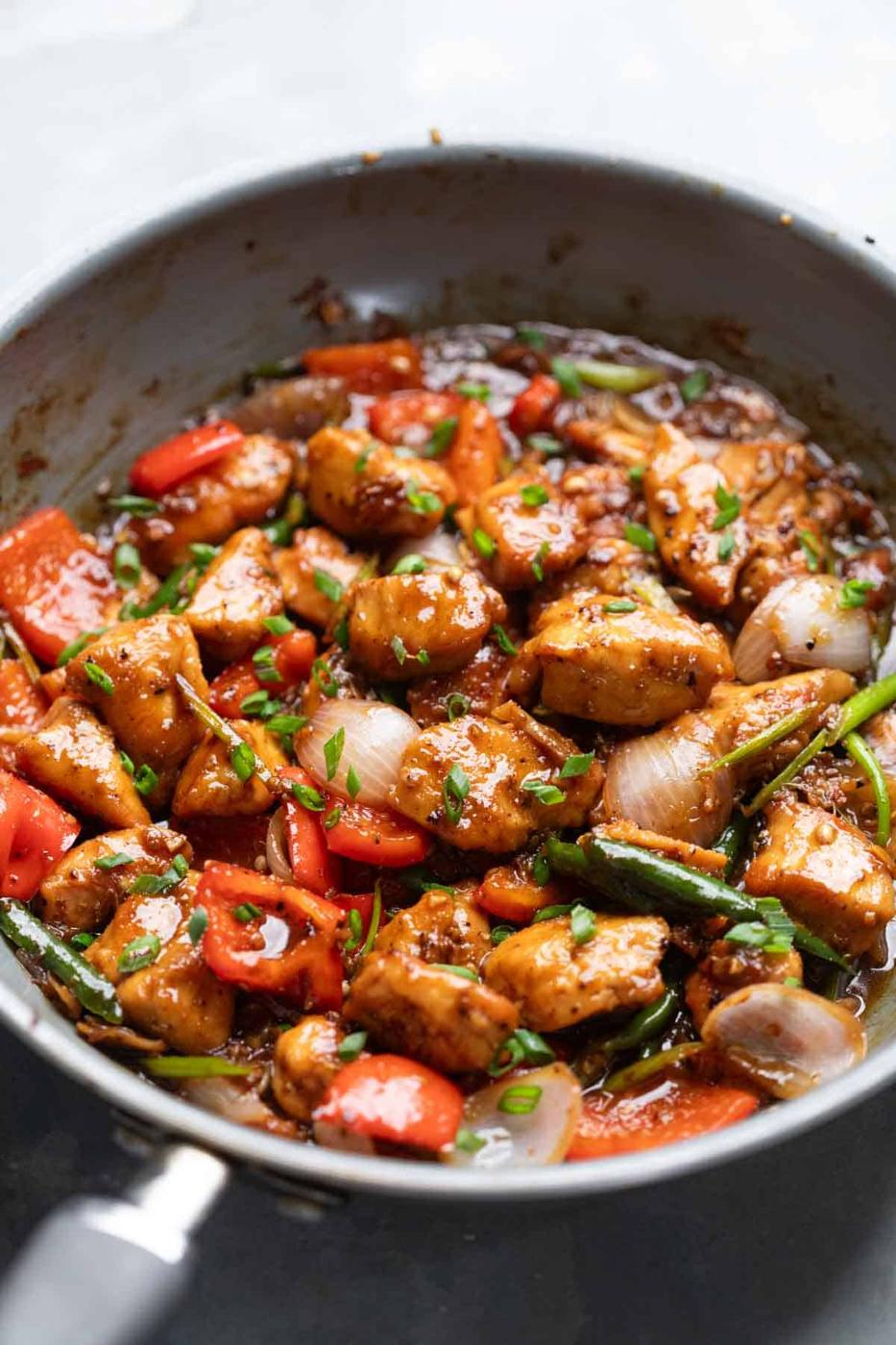 close up of black pepper chicken being cooked in a pan