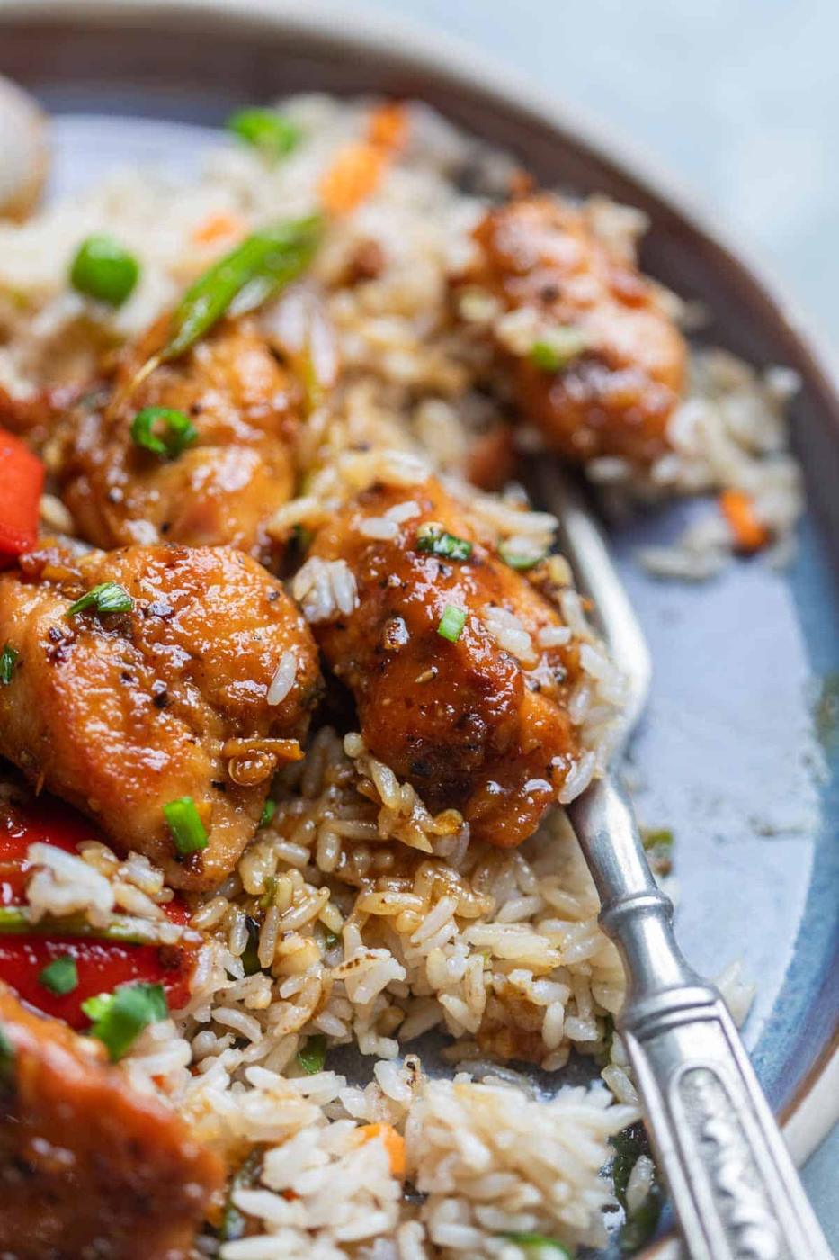 close up of air fryer black pepper chicken poured over rice on a plate