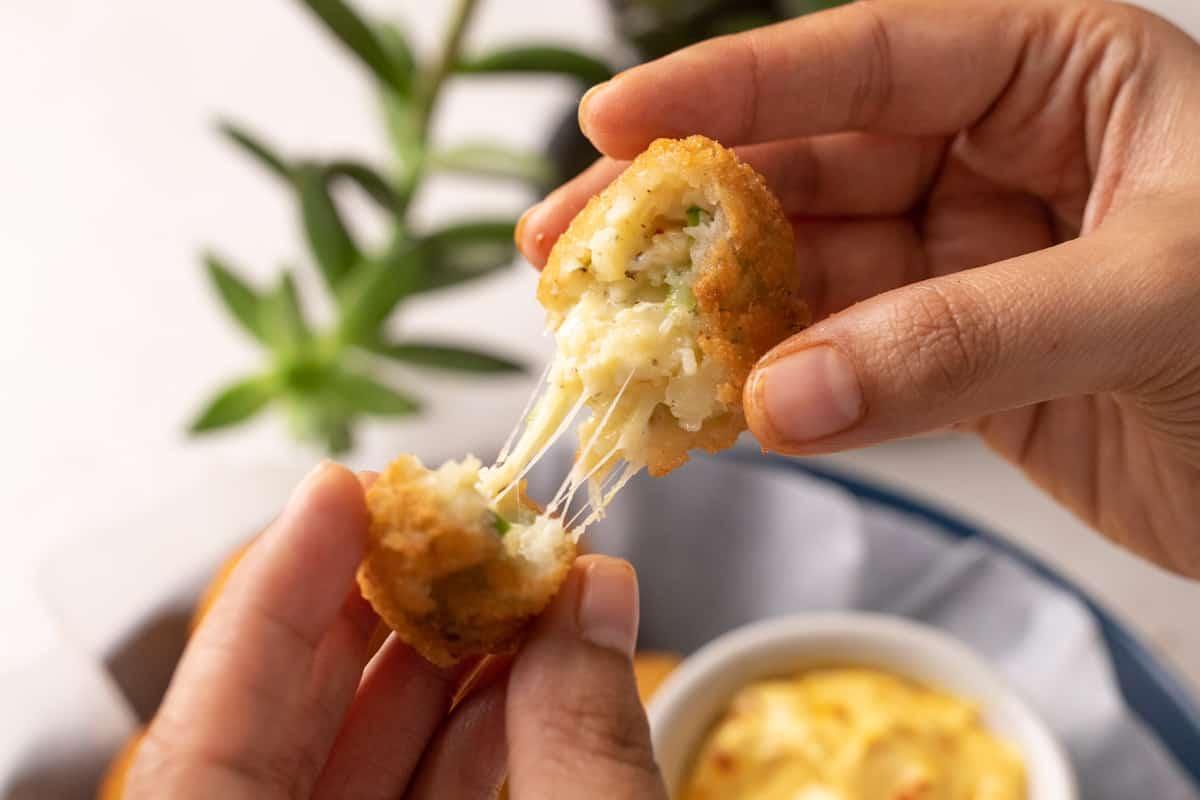 Picture of hands breaking a cheese ball apart to show the cheese pull