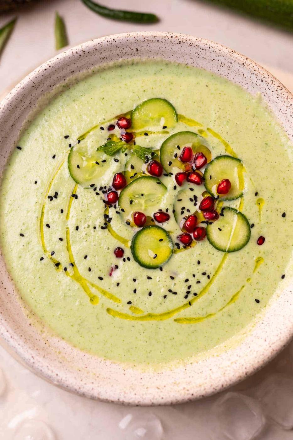 cold cucumber soup garnished with cucumber slices, pomegranate and nigella seeds ready to be served