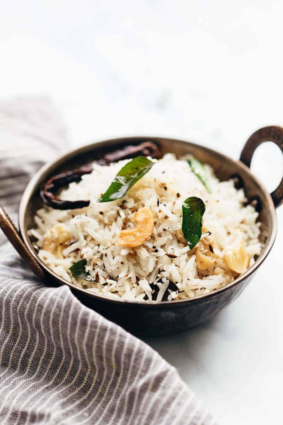 Coconut rice served in a kadhai topped with roasted cashews and curry leaves