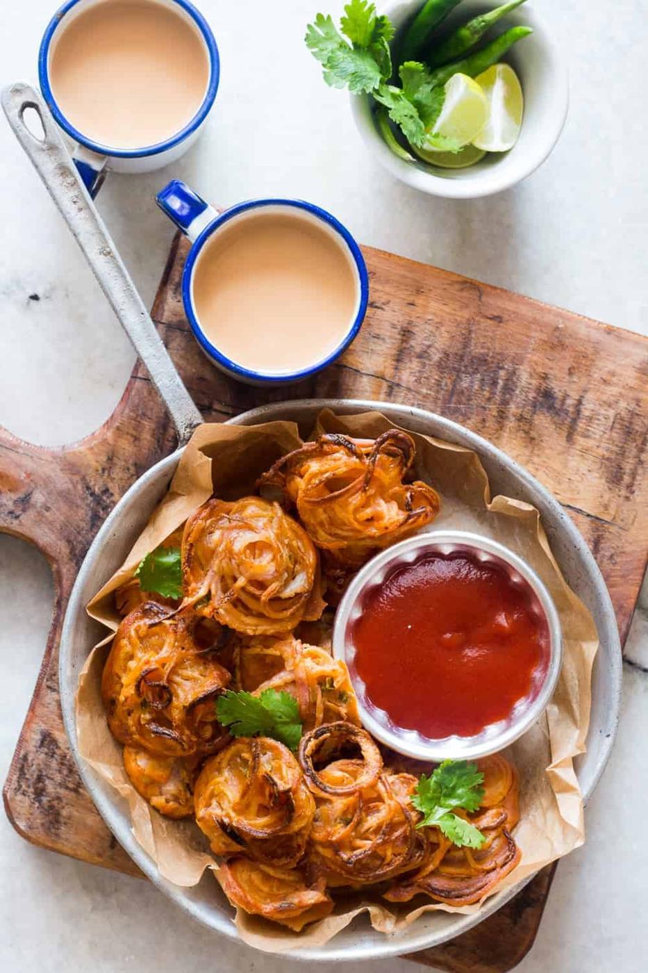 Indians love their pakodas and bhajiyas (fritters) and now there's a guilt-free way to enjoy them with a cup of masala chai. Nobody's ever going to believe these onion pakodas are baked, not fried! Can be made with potato, corn, capsicum and paneer too!