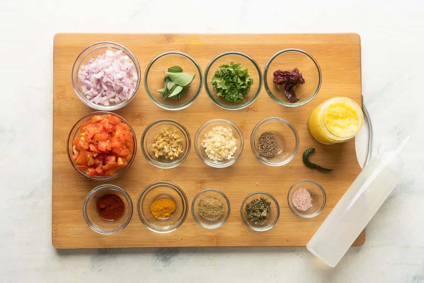 Ingredients required for dal tadka laid out on a wooden chopping board