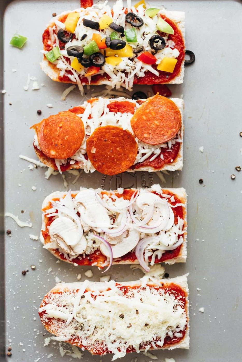 Toppings on french bread pizza toasts about to go into the oven