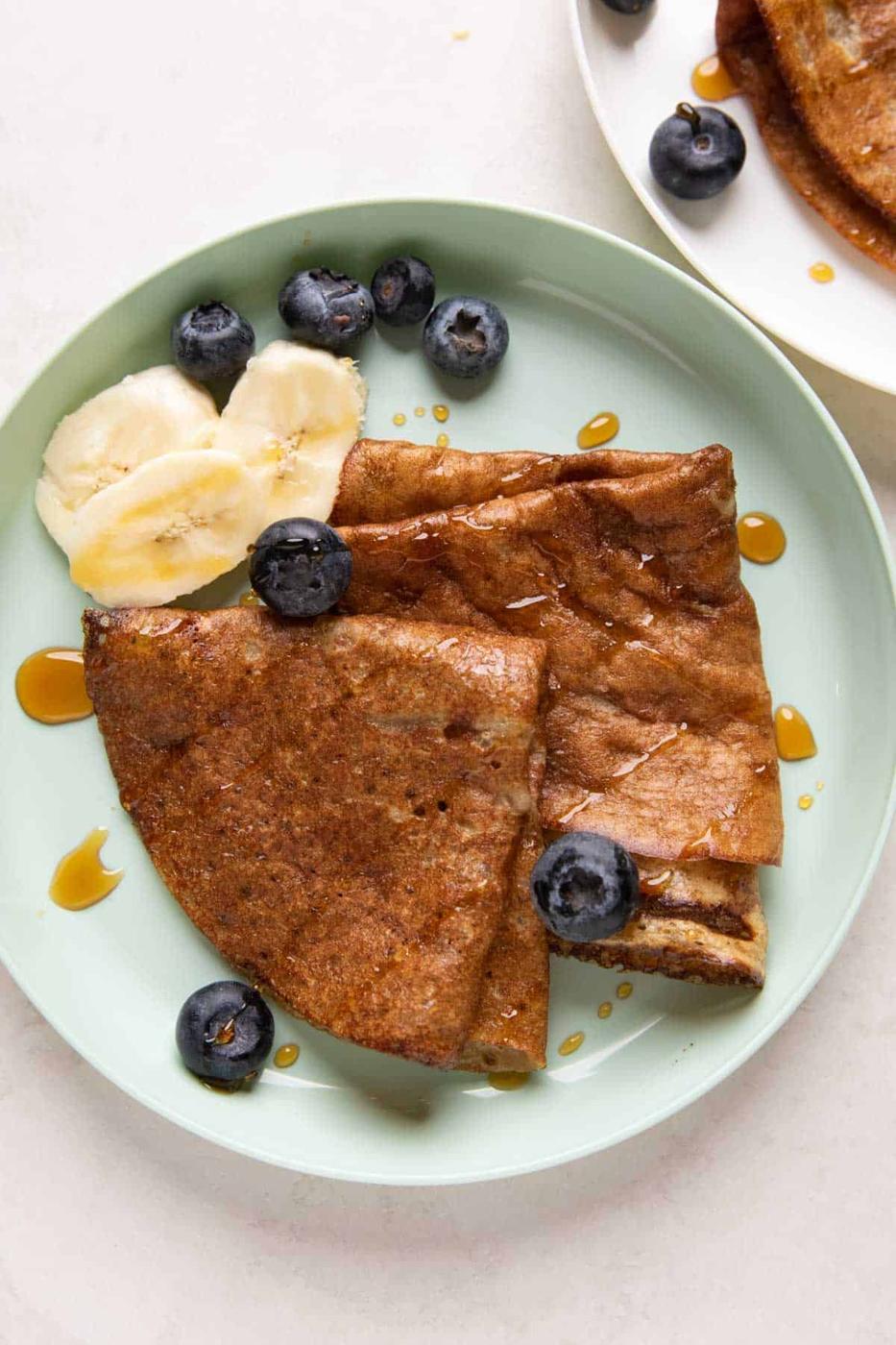 Banana Dosa served on a green kids plate with bananas, honey and blueberries on the side