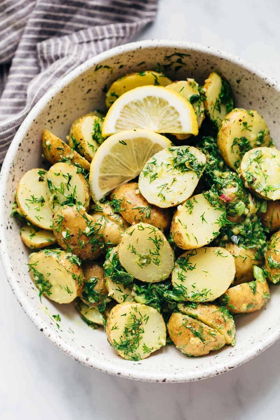 Healthy Lemon Dill Potato Salad (no mayo) served in a white speckled bowl with lemon wedges