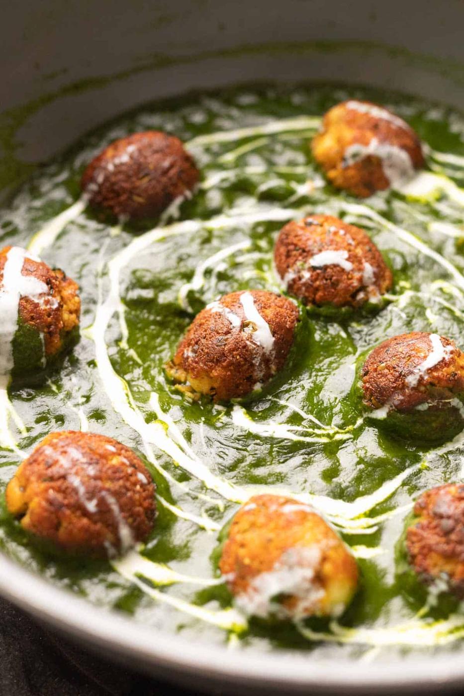 The Healthy Palak Paneer Kofta Curry in a pan with cream drizzled on top