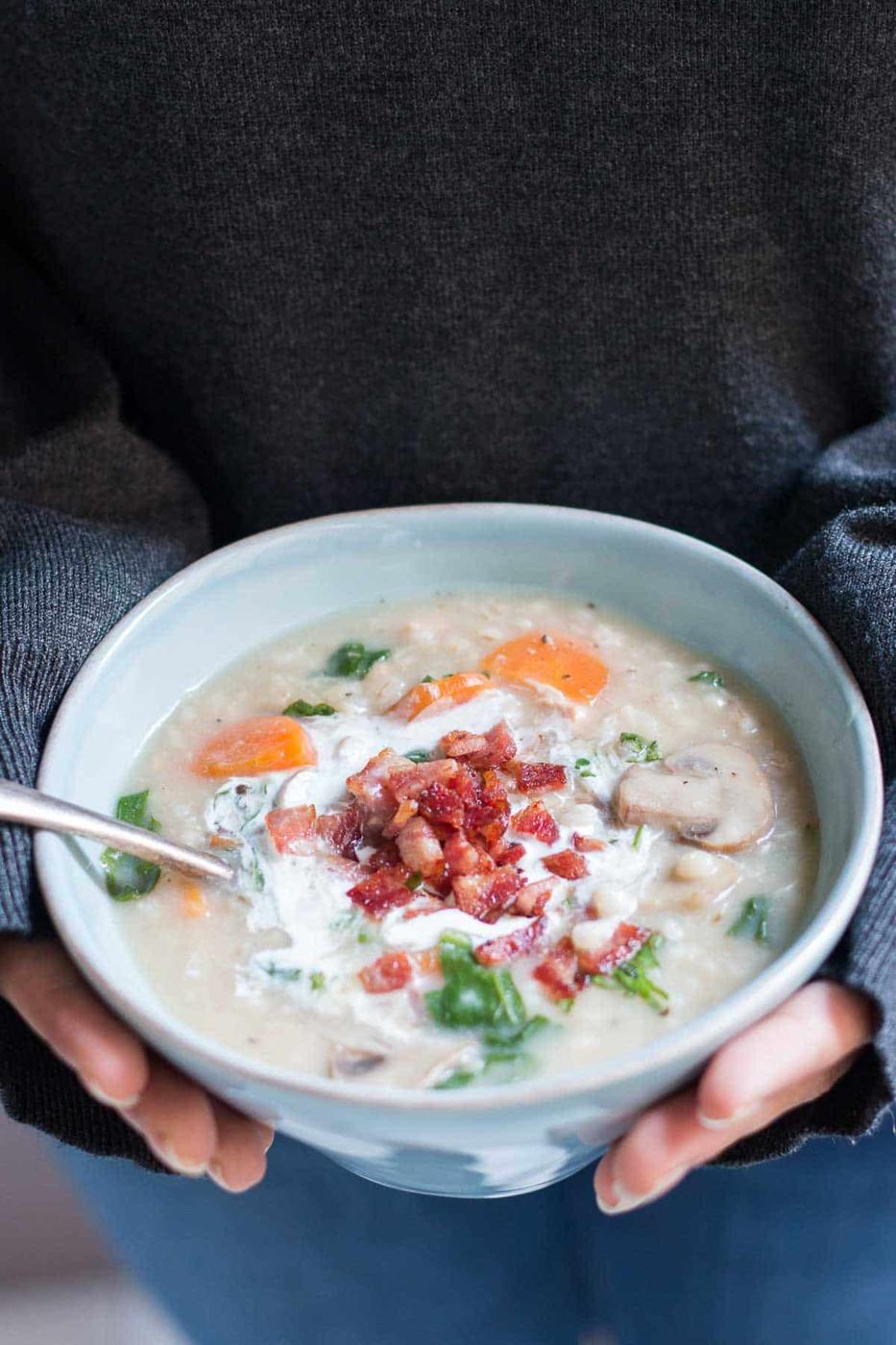 The soup garnished with bacon and cream and served in a white bowl.
