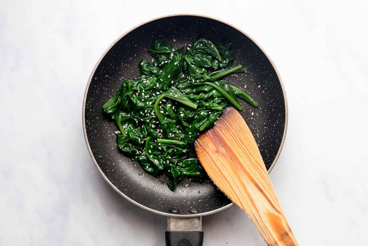 Sauteed Spinach in a pan topped with sesame seeds
