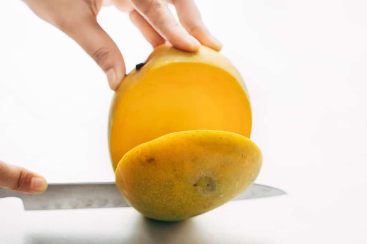 Cheeks of a mango being cut out.