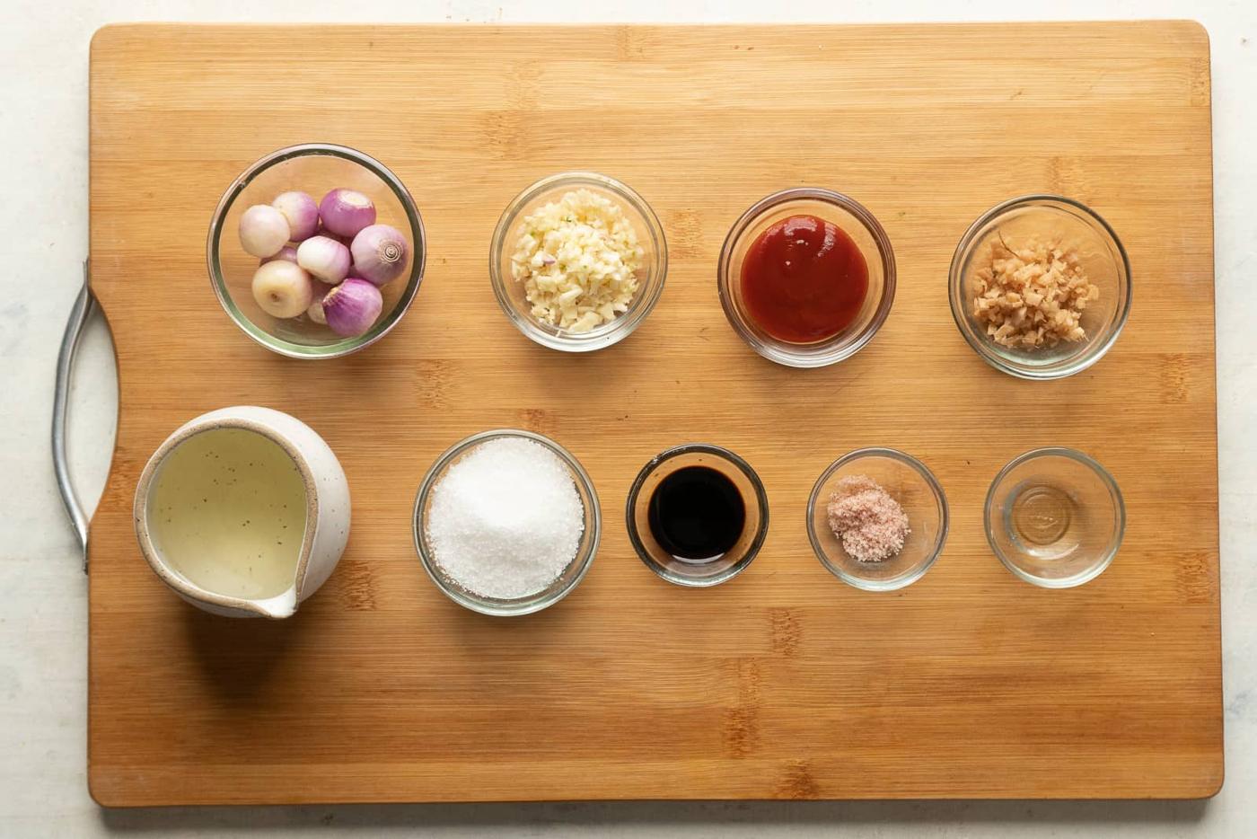 All the ingredients required for schezwan sauce are pictures on a wooden board, except chillies and hot water