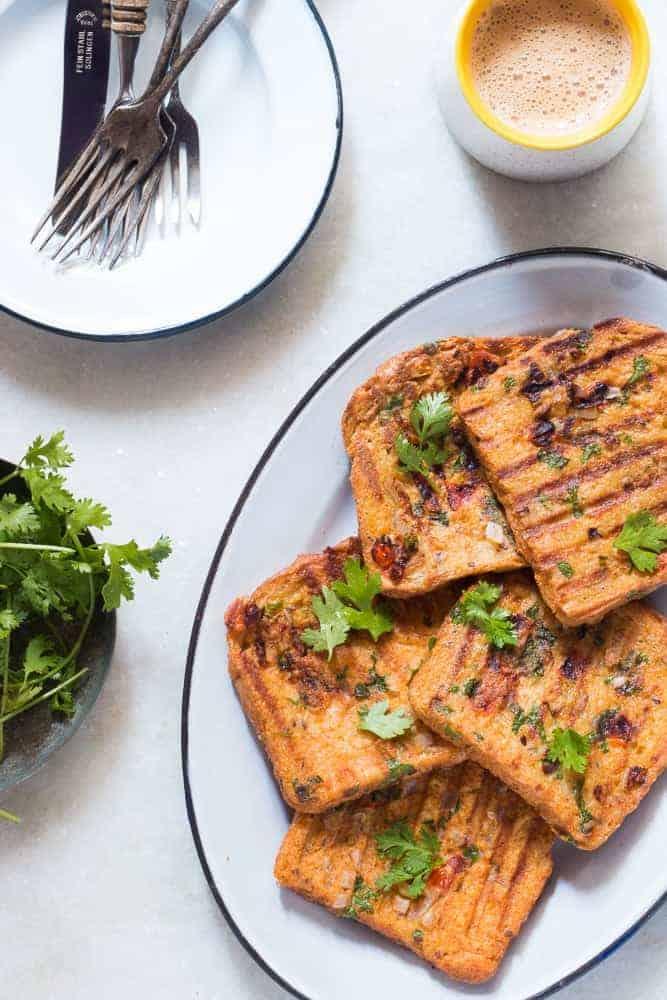 Indian masala egg french toast served in a white plate with hot cups of coffee on the side