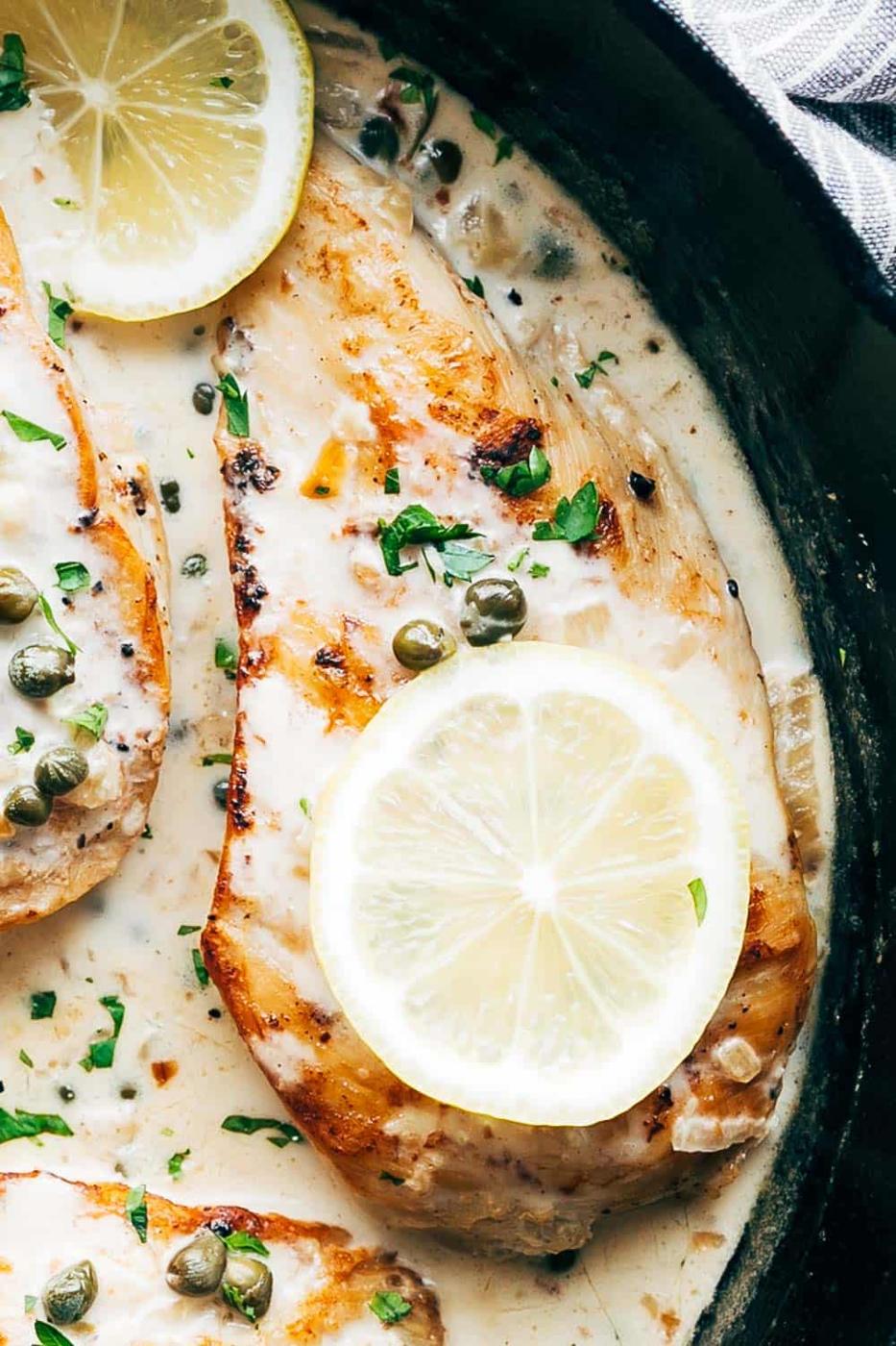 Closeup of creamy lemon chicken scallopini with lemon slices and capers on top