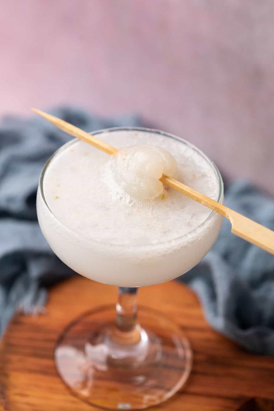lychee soda served in a glass topped with lychee on a toothpick