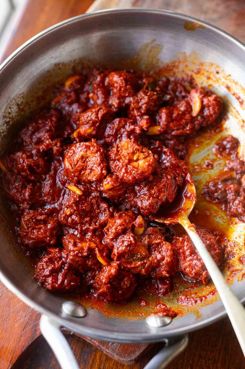 Prawn Pickle in a pan with a spoon showing a pickled prawn