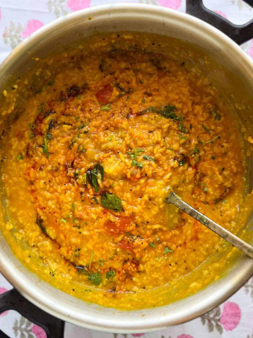 one pot sambar rice scooped up in a ladle to showcase it's color and texture