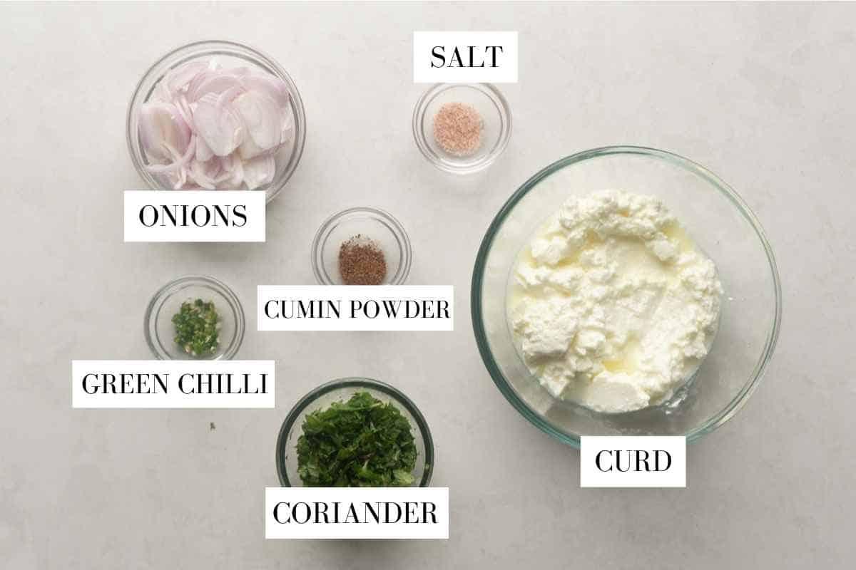 Picture showing all the ingredients for onion raita with text to identify them