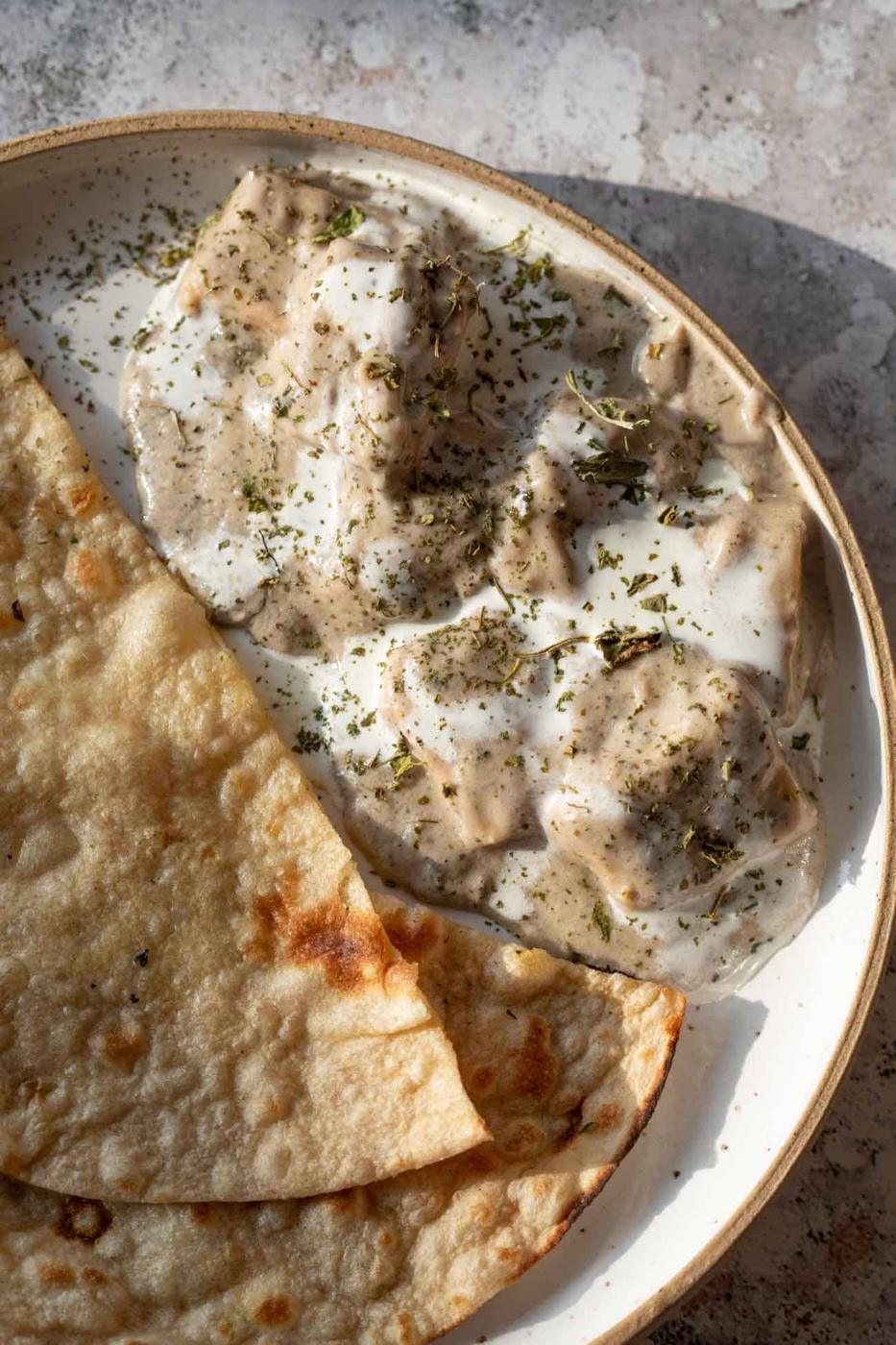 paneer kali mirch gravy served in a bowl with cream drizzled on top served with roti