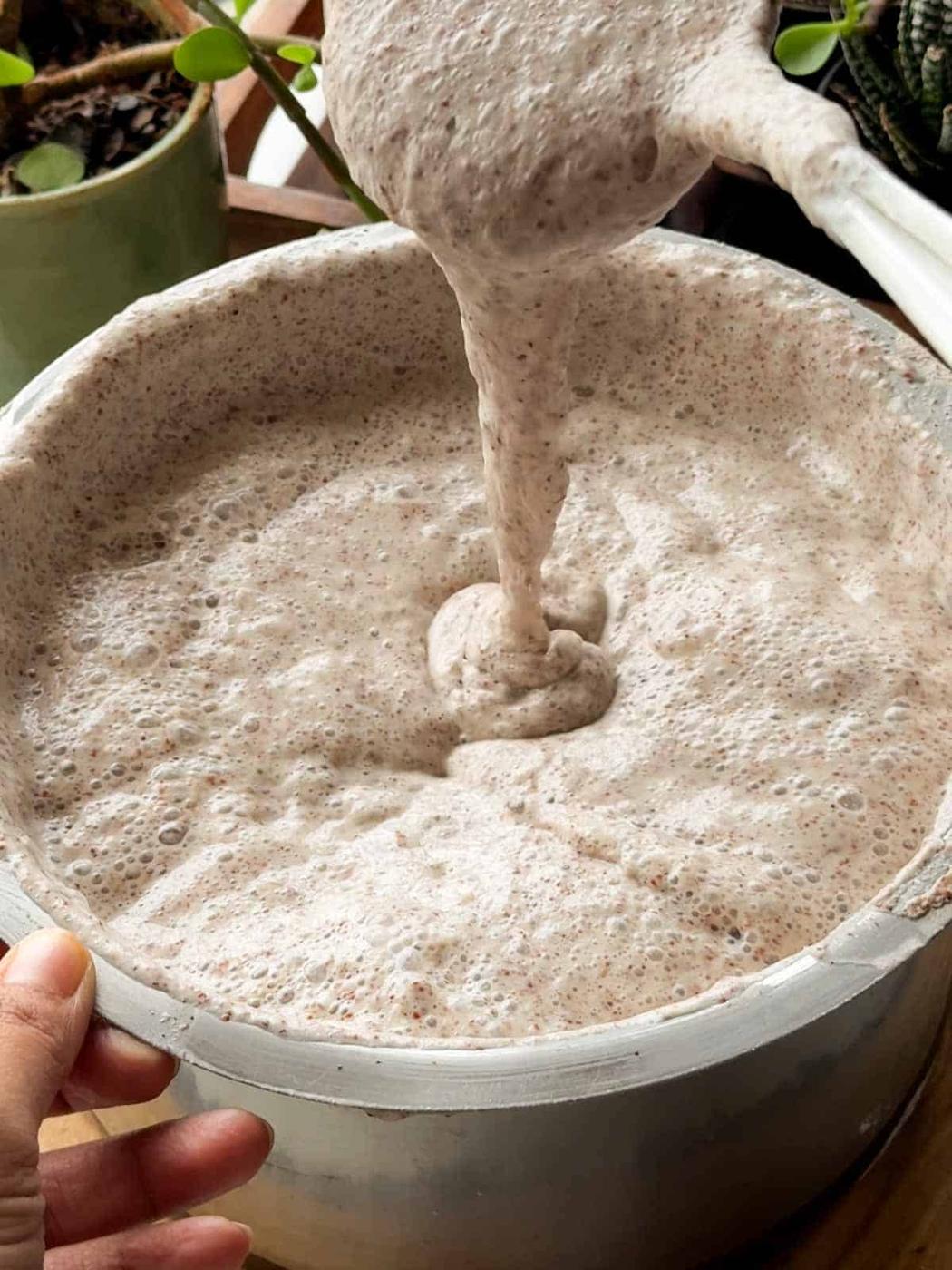 an image fermented ragi dosa batter being poured to show it's consistency