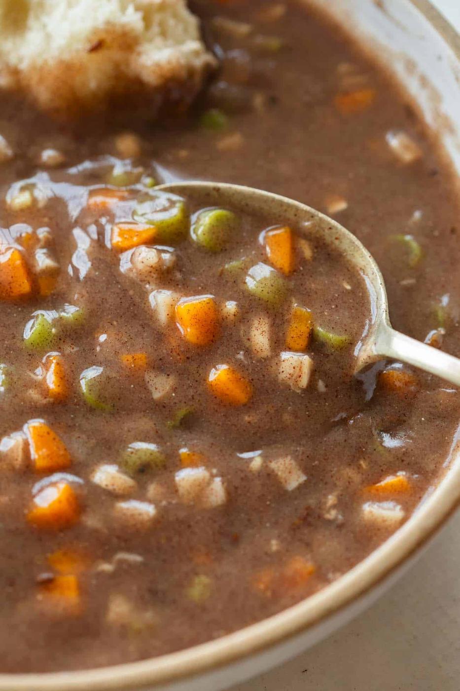 a whole bowl with ragi soup with diced carrots and beans with a spoon