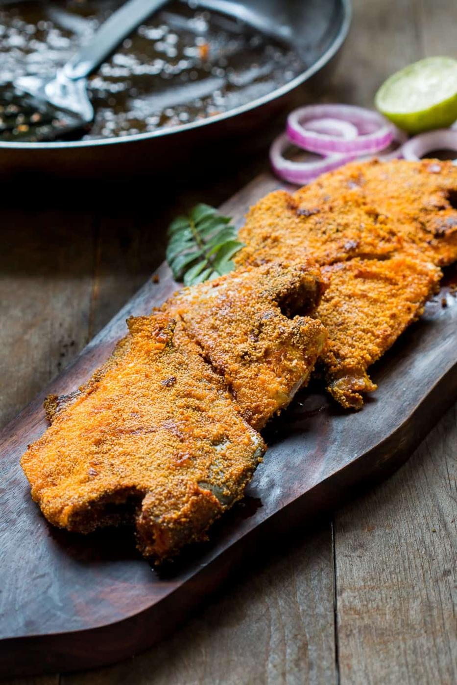 the fried fish coated with rava aka semolina served on a wooden board