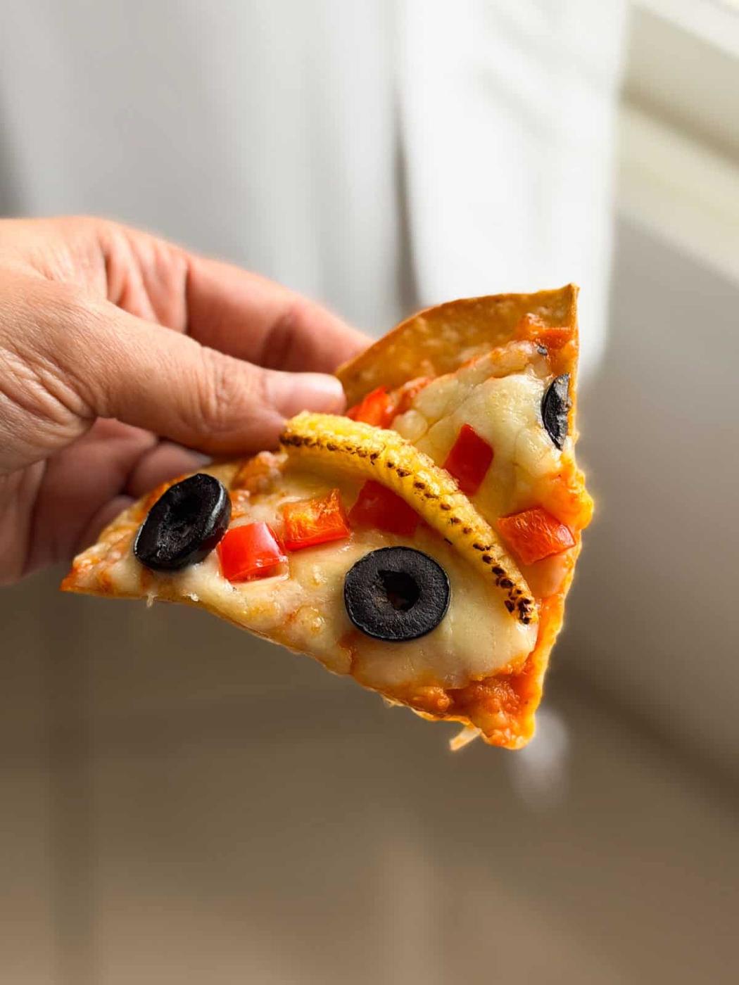 a person holding a slice of air fryer roti pizza