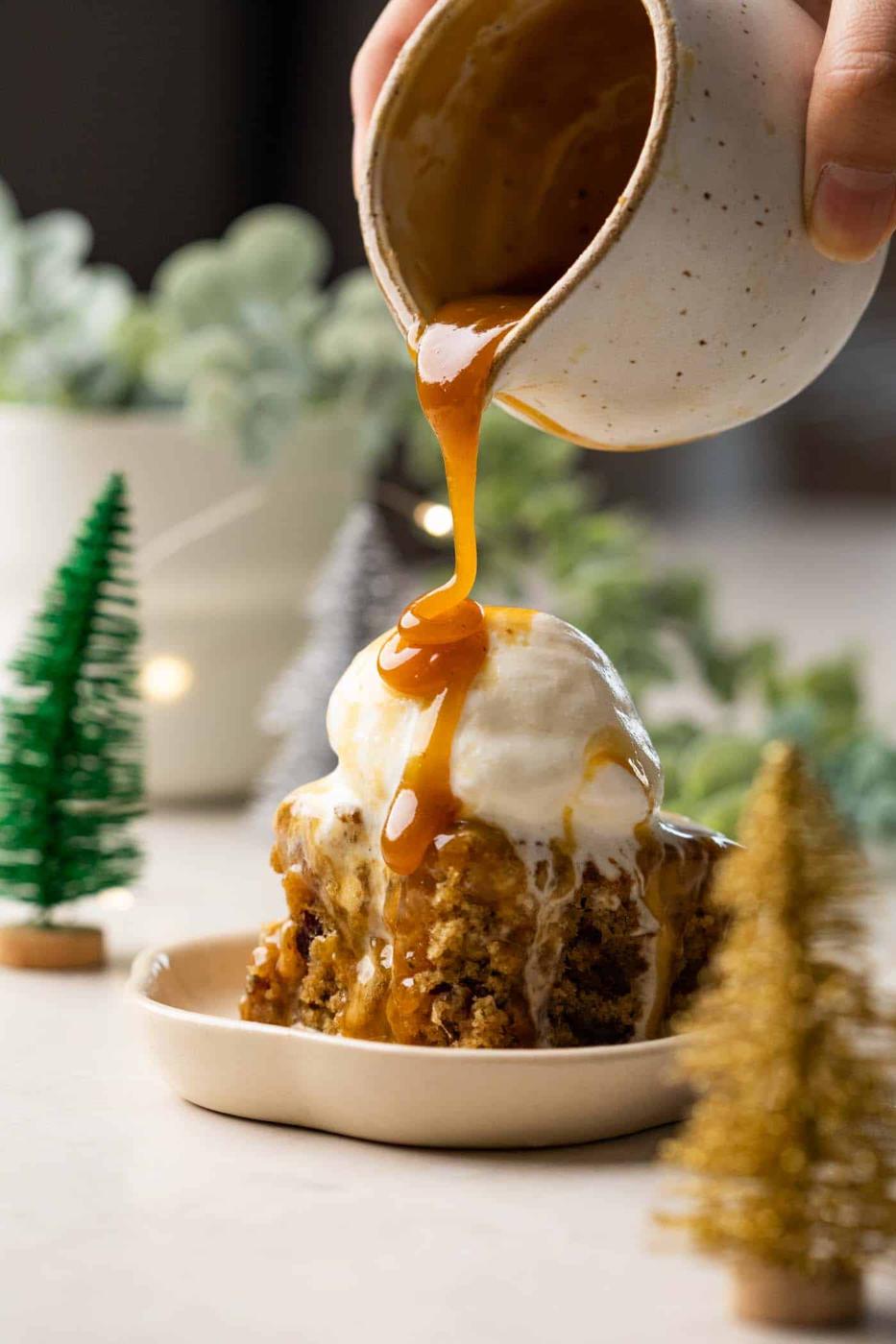 Toffee sauce being poured on sticky toffee pudding