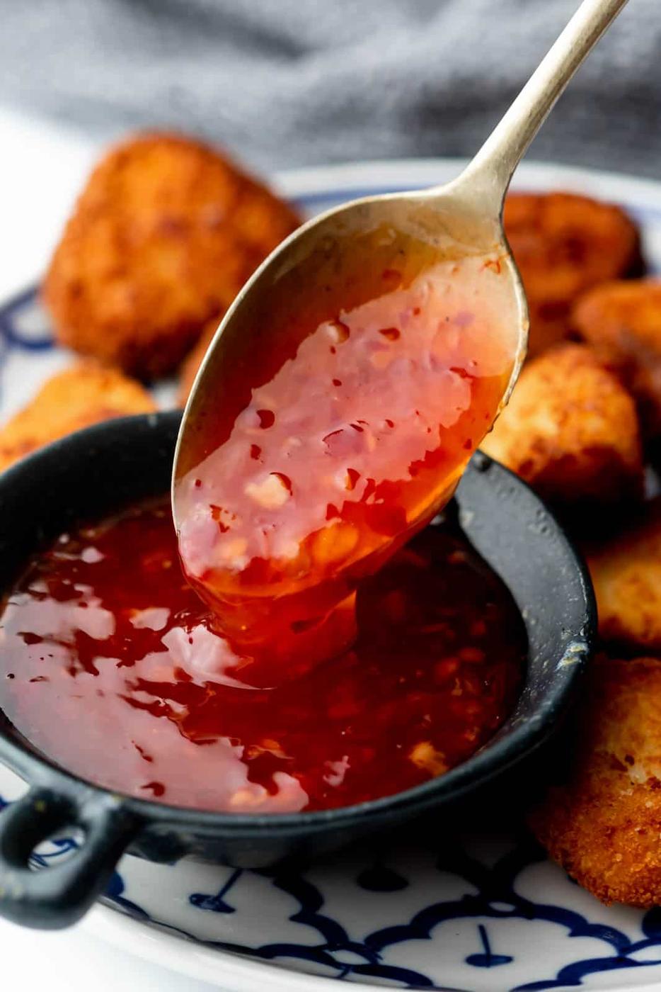 Closeup of Thai sweet chili sauce dripping off a spoon to showcase the shiny, sweet, sticky texture
