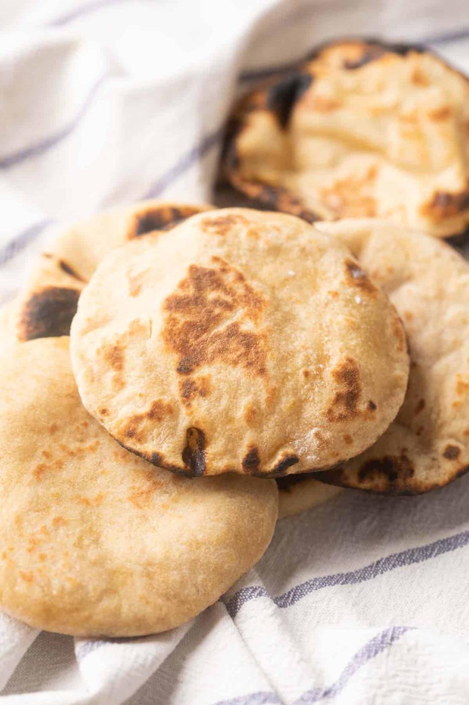 Picture of Whole wheat pita breads kept on a striped white kitchen cloth