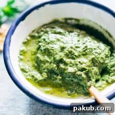 Vibrant green basil walnut pesto in a white bowl, ready to be served.