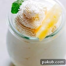 Eggless Pineapple Mousse garnished with mint and a slice of pineapple and served in a mini jar.