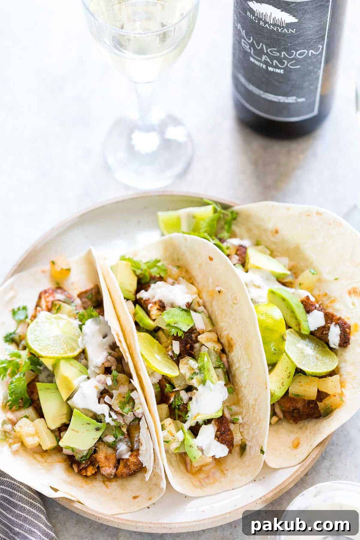 Sunshine Tilapia Tacos with Pineapple Salsa Burst 5 Tilapia Fish Tacos with Pineapple Salsa served on a white plate with a side of Big Banyan's sauvignon blanc.