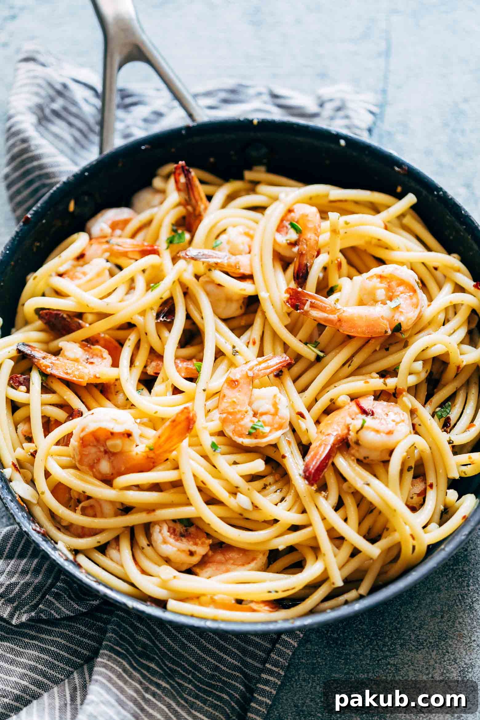 A vibrant bowl of Shrimp Spaghetti Aglio Olio, garnished with fresh parsley and a hint of red chili flakes, showcasing perfectly cooked spaghetti intertwined with juicy shrimp in a glossy garlic-infused olive oil sauce.