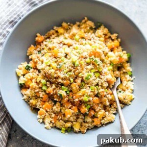 Low Carb Asian Cauliflower Rice topped with sesame seeds, chopped green onions and served in a bowl.