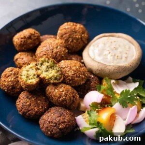 Crispy falafels served in a blue bowl with tahini dip and salad on the side