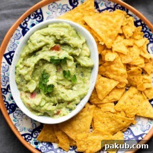 Crazy good homemade guacamole served in a white bowl with chips on the side