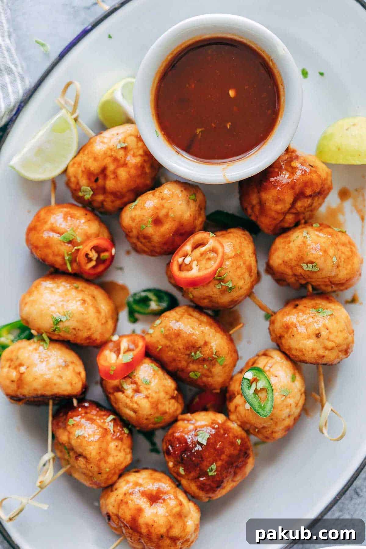 Dynamite Glazed Chicken Meatballs 3 Close-up of golden-brown baked chicken meatballs simmering in a glossy, thick firecracker sauce in a pan.