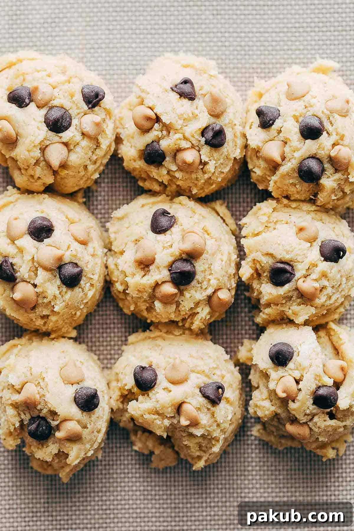 Pumpkin Snickerdoodle Cookie dough scooped onto a parchment-lined baking sheet, ready for rolling in cinnamon sugar and baking.