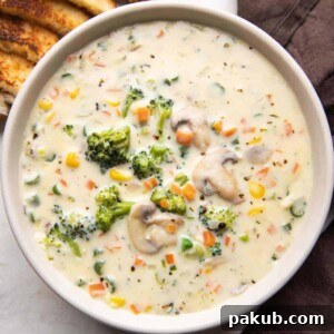 Creamy vegetable soup served in a bowl with bread on the side