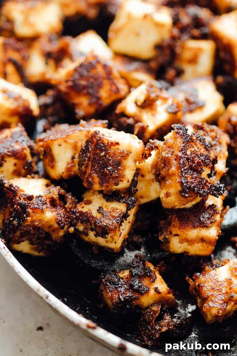 crispy sesame tofu cooking in a pan with delicious browned sauce