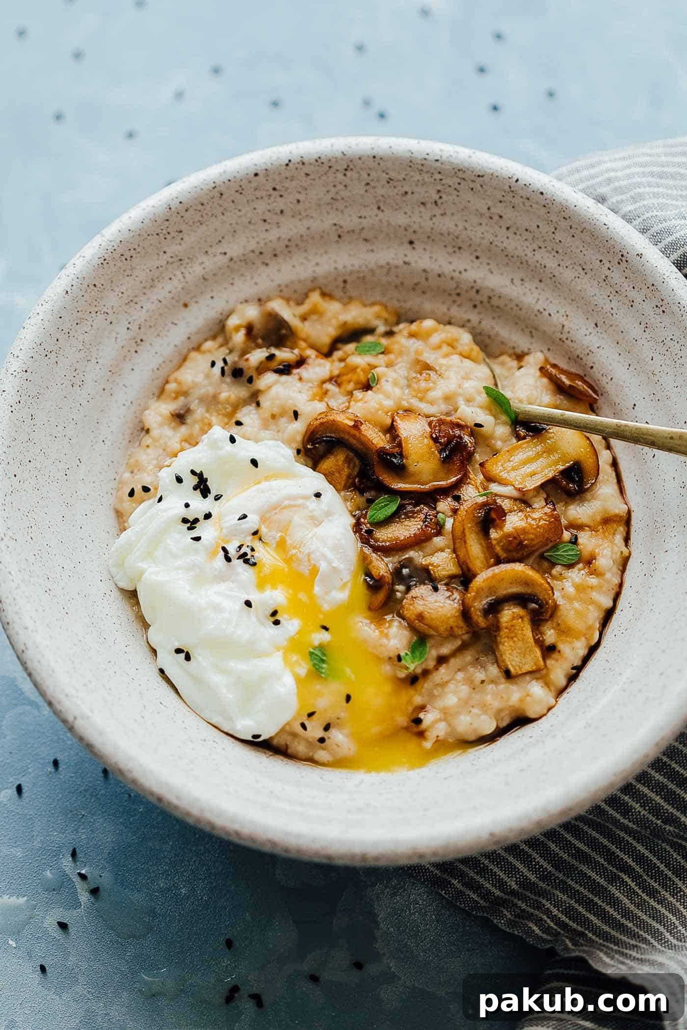 Beyond Sweet: 5 Savory Oatmeal Breakfast Recipes 6 Creamy mushroom oats served in a bowl, topped with a poached egg, a dash of soy sauce, and chopped green onions for an Asian-inspired savory breakfast.