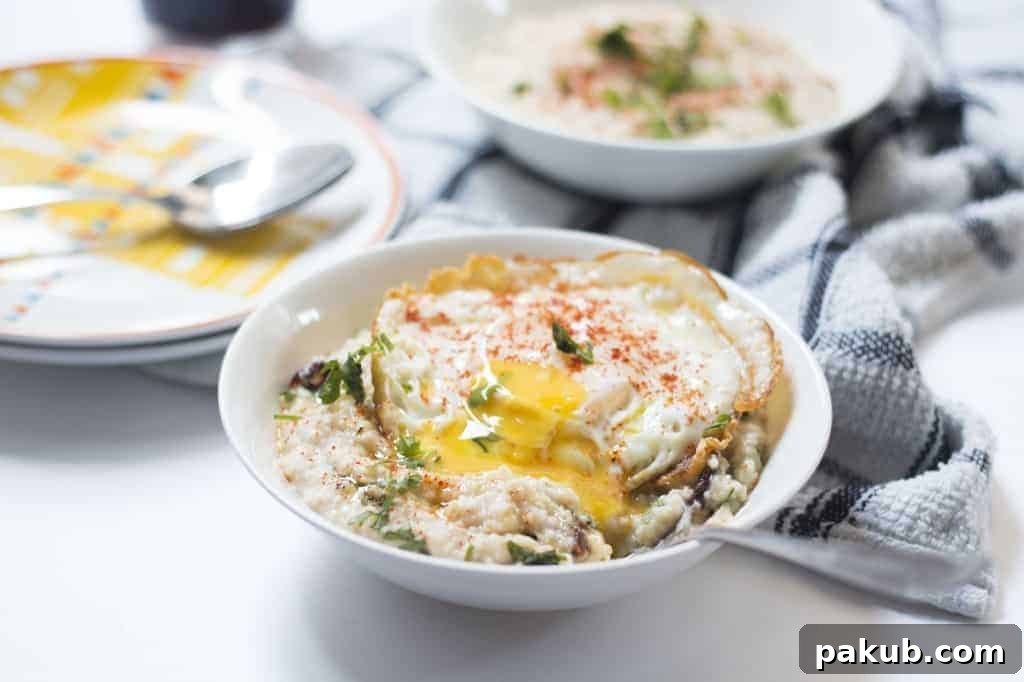 Beyond Sweet: 5 Savory Oatmeal Breakfast Recipes 4 Creamy garlic oats topped with two perfectly fried eggs, seasoned with paprika and fresh coriander for a high-fiber, high-protein breakfast.