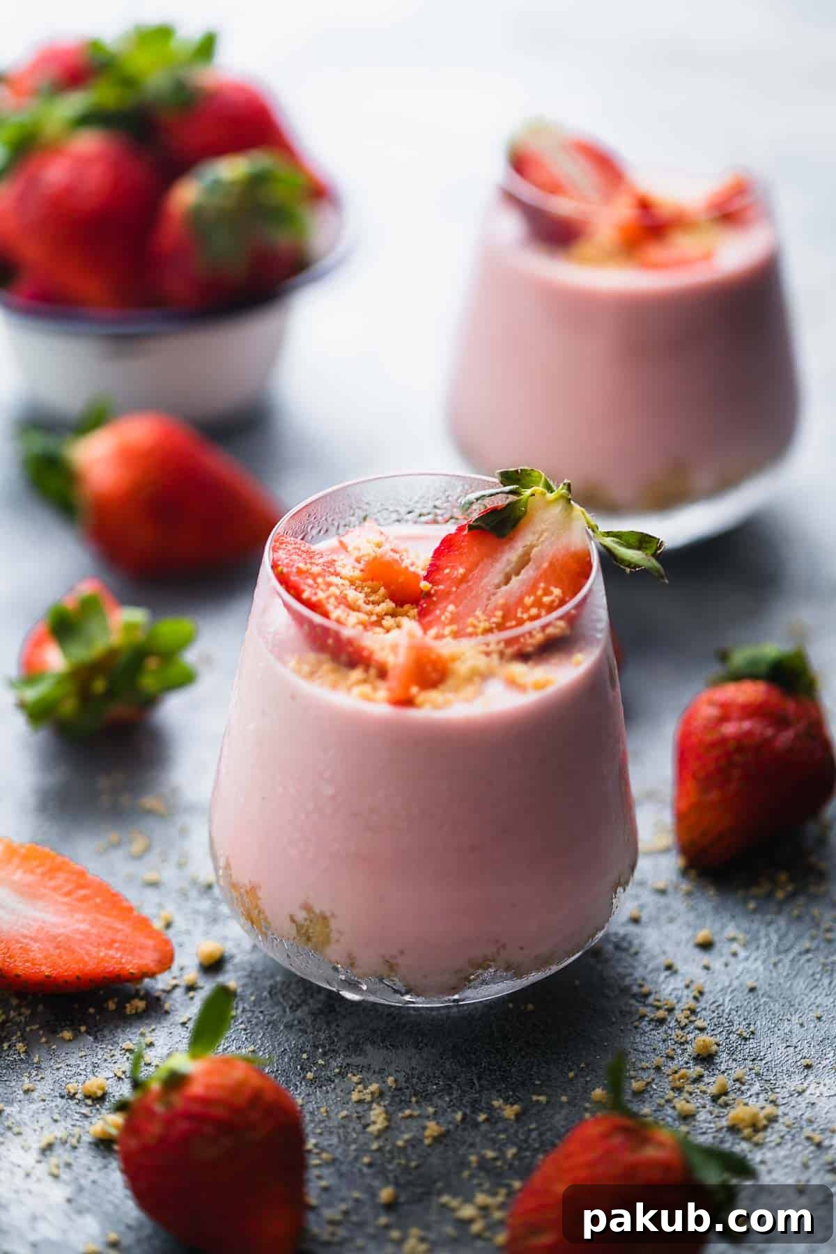 No Fuss Strawberry Cheesecake Jars 2 Two beautifully layered No-Bake Strawberry Cheesecake Jars, garnished with fresh whole strawberries and scattered berries around them, showcasing their creamy texture and vibrant color.
