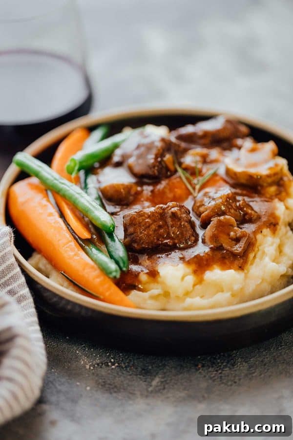 Effortless Pressure Cooker Beef Bourguignon 2 Rich Pressure Cooker Beef Bourguignon served over creamy mashed potatoes, garnished with fresh herbs, alongside vibrant green beans and carrots.