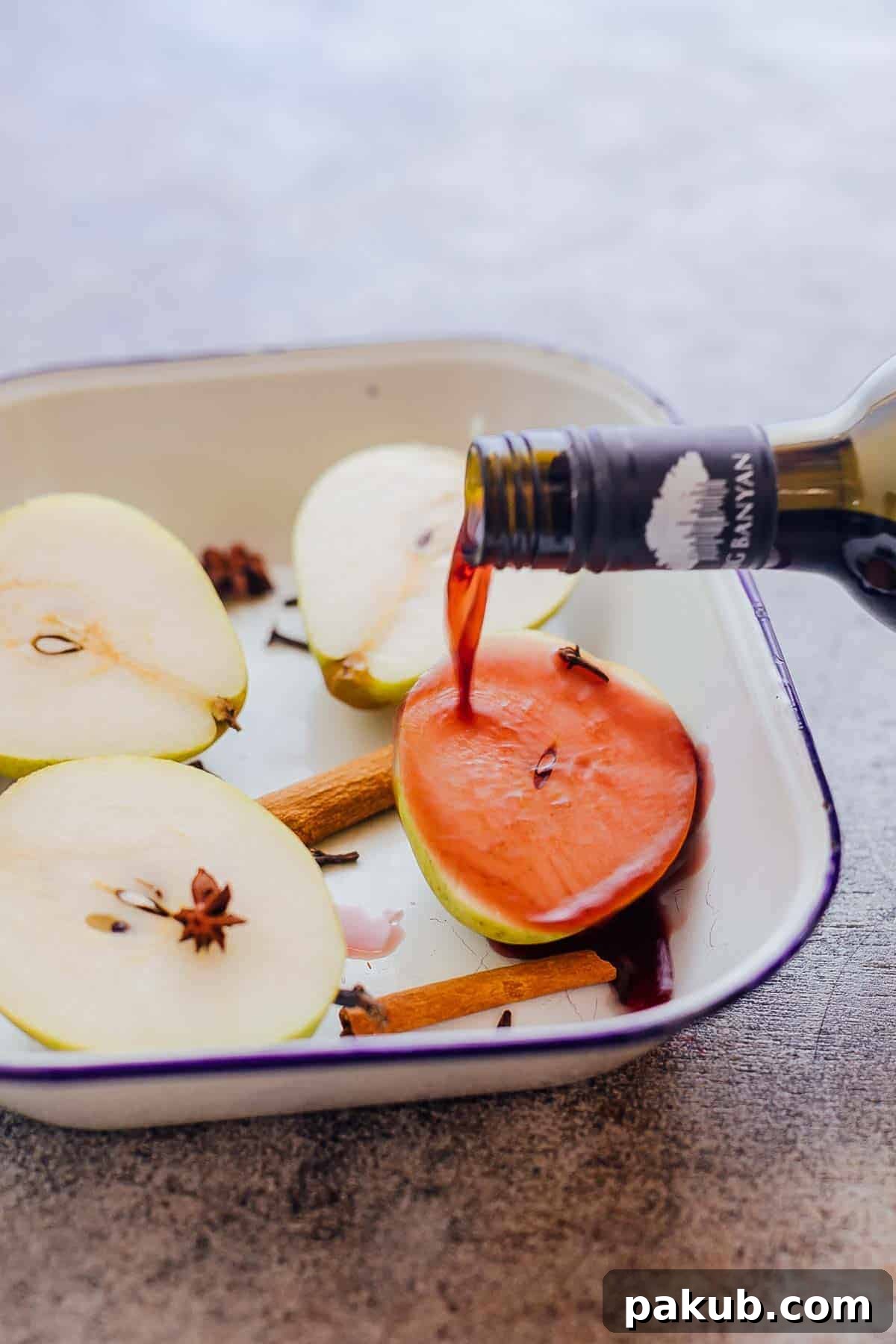 Beautifully poached pears in red wine, elegantly garnished with cinnamon sticks and star anise, showcasing a classic dessert made with wine and spices.