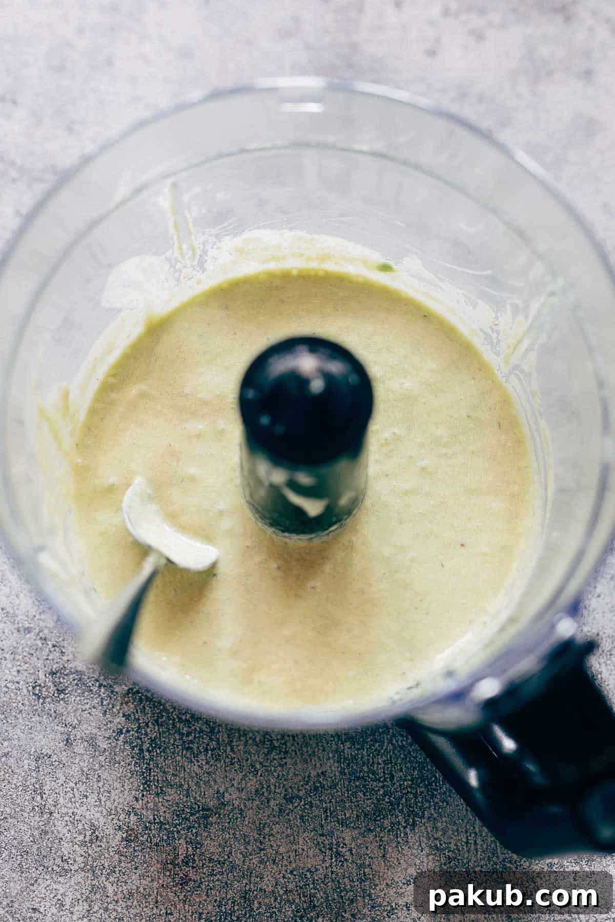 The secret to an exceptional Cobb Salad: a perfectly blended, lighter avocado blue cheese dressing made with Greek yogurt for a tangy, creamy finish. Close-up of the creamy avocado blue cheese dressing in a blender, showing its smooth, vibrant green texture with specks of blue cheese, ready to be drizzled over a fresh Cobb salad.