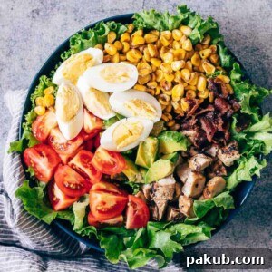 The complete Chicken Cobb Salad, a perfect blend of fresh and savory elements, enhanced by a creamy avocado blue cheese dressing. A vibrant Chicken Cobb Salad artfully arranged in a bowl, showcasing fresh ingredients like mixed greens, grilled chicken, crispy bacon, boiled eggs, cherry tomatoes, and avocado, all ready for the delicious blue cheese dressing.
